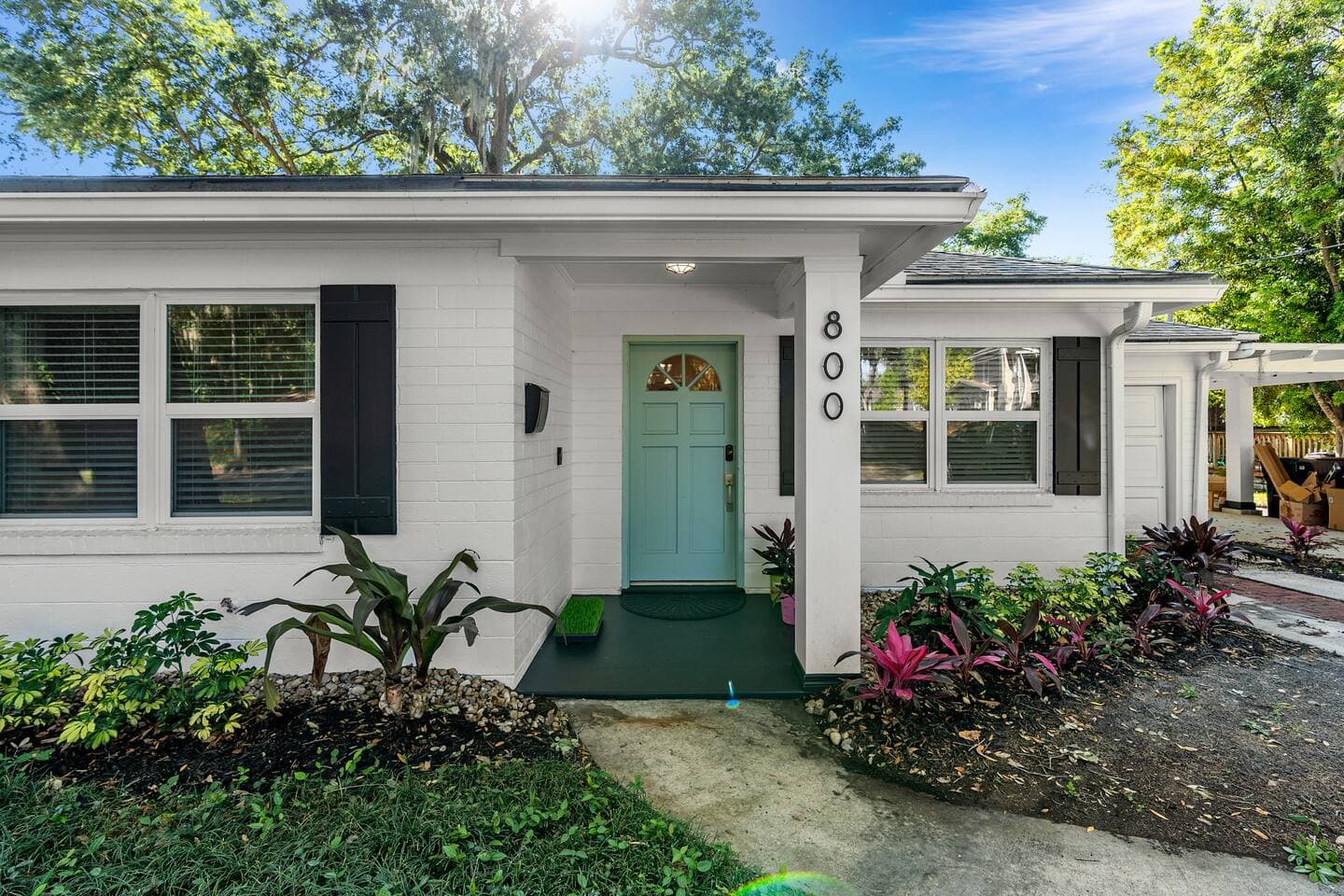 Charming front entrance with turquoise door and lush Florida greenery