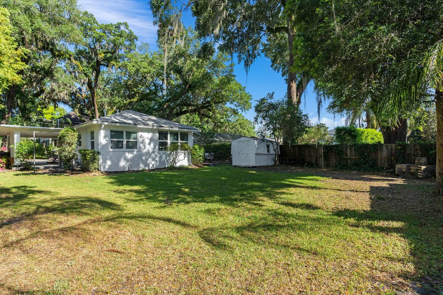 Sunny backyard lawn with mature trees and privacy fence – Pet friendly